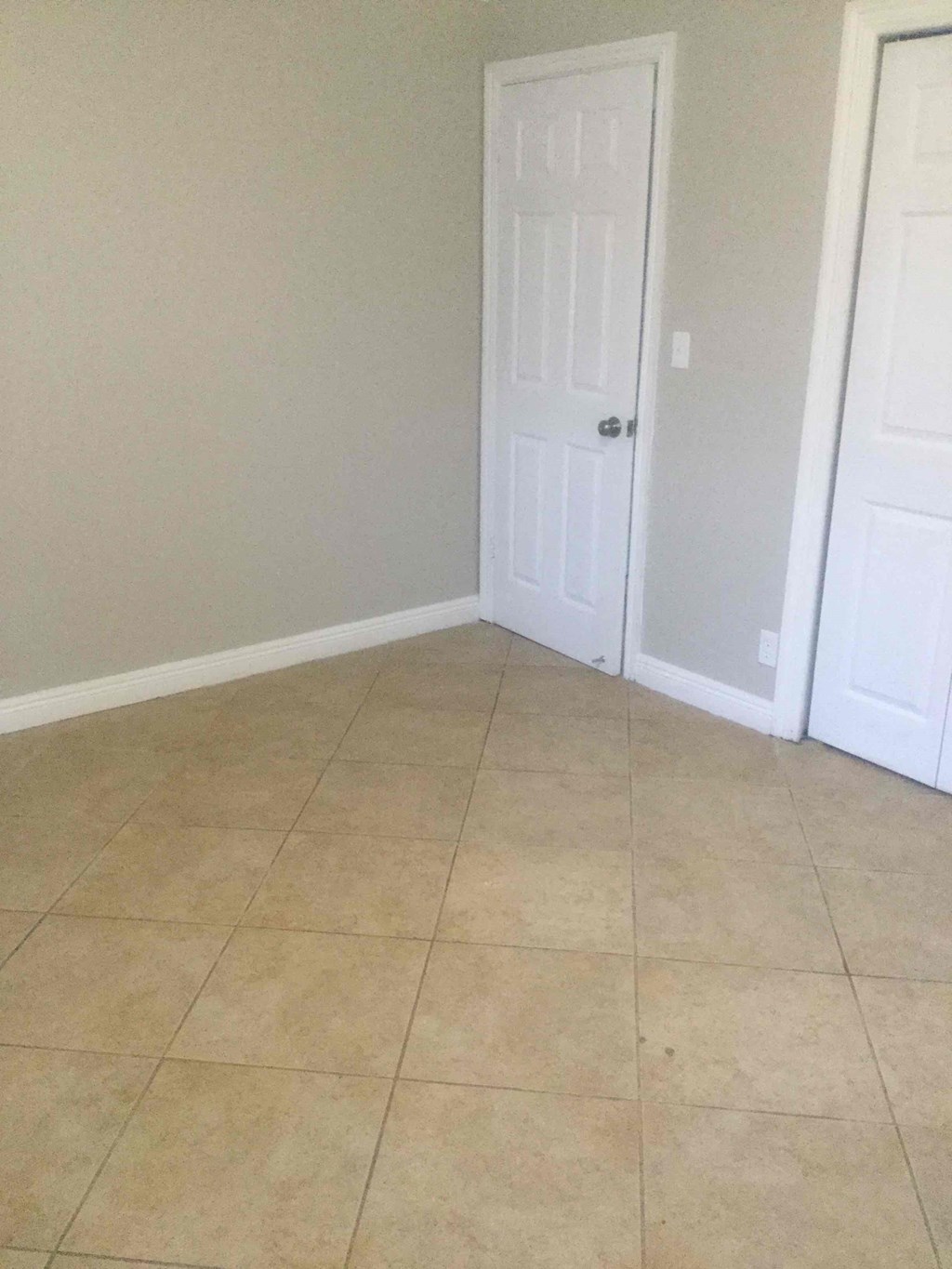 A room with a white door and tiled floor.