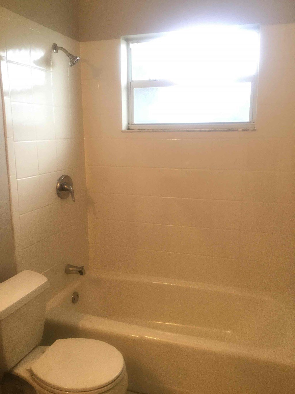 A white toilet sits next to a bathtub in a bathroom.