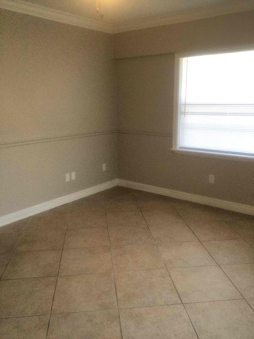 A room with a window and tile flooring.
