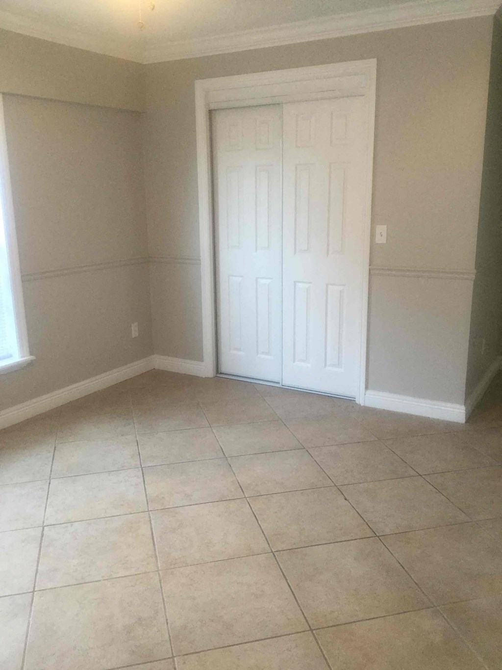 A room with a white door and tiled floor.