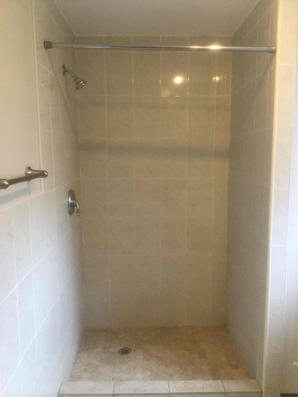A white tiled shower with a glass door.