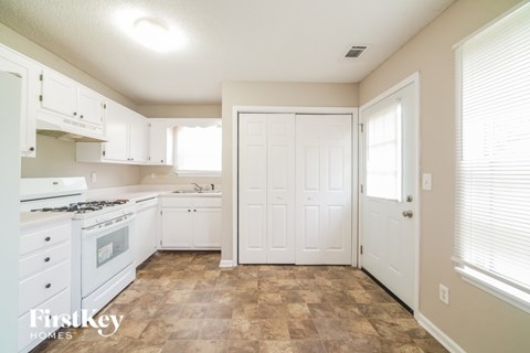 A kitchen with white cabinets and a tiled floor.