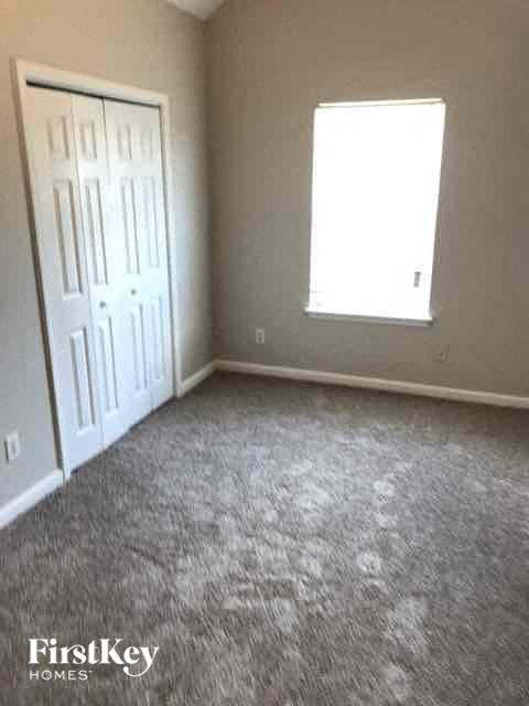 A room with a carpeted floor, a door, and a window.