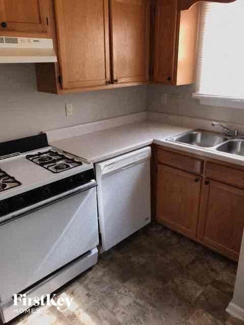 A kitchen with a white stove top oven and white dishwasher.