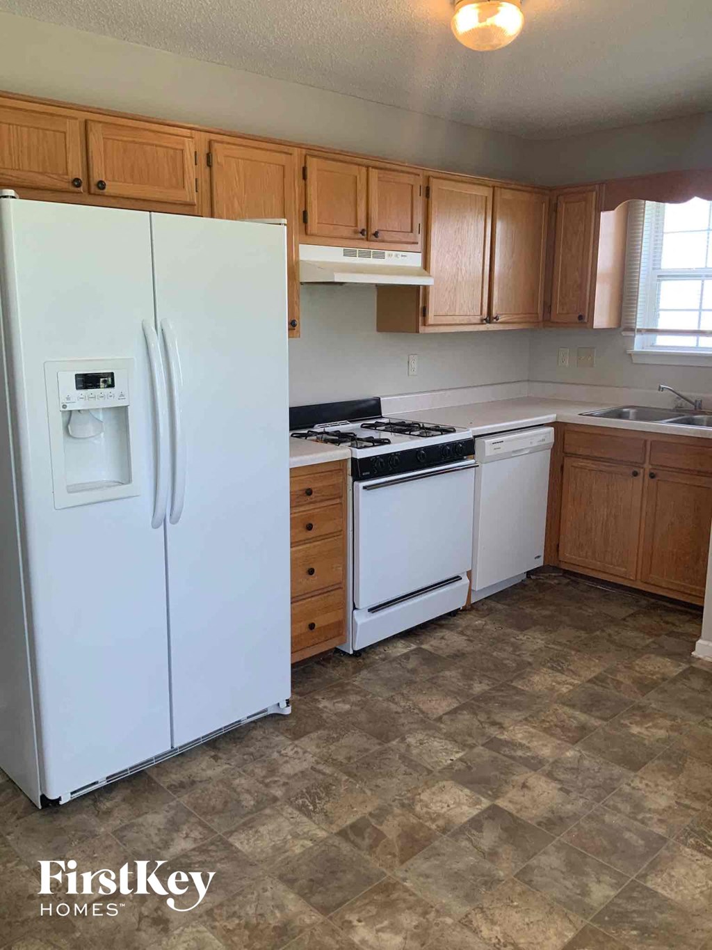 A kitchen with a white fridge and wooden cabinets.