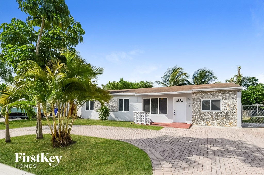 A house with a white door and a brick driveway is for sale.