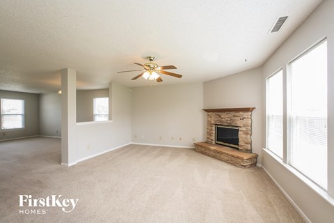 an empty living room with a fireplace and a ceiling fan