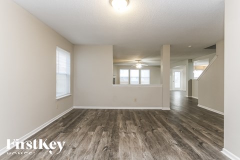 A spacious room with wooden flooring and white walls.