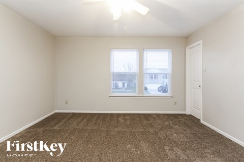 A room with a carpeted floor and a window with a view of a building outside.