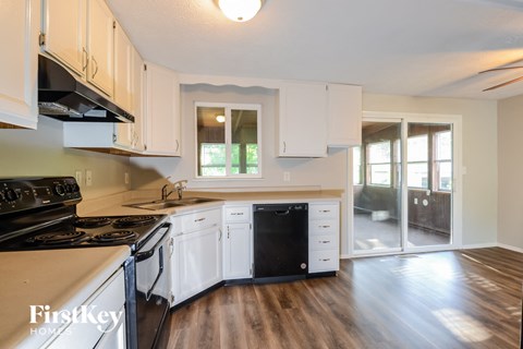 a kitchen with white cabinets and black appliances and a sliding glass door