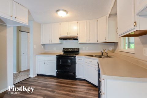 an empty kitchen with white cabinets and black appliances