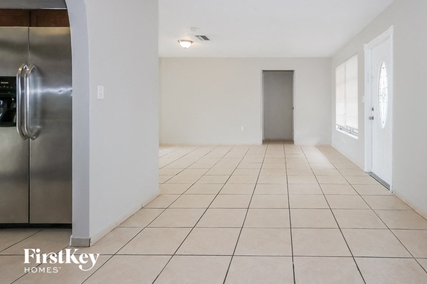 A spacious room with a tiled floor and a refrigerator on the left side.