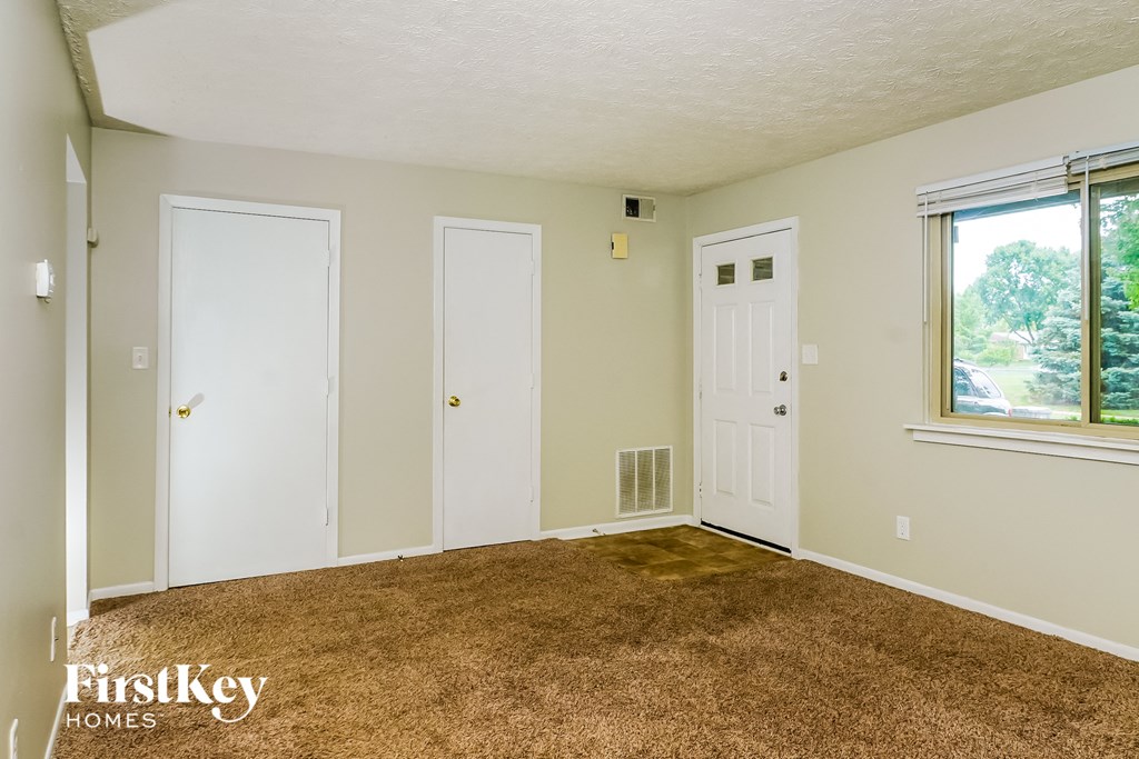 a living room with a carpet and two doors and a window