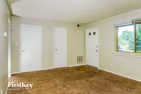 a living room with a carpet and two doors and a window