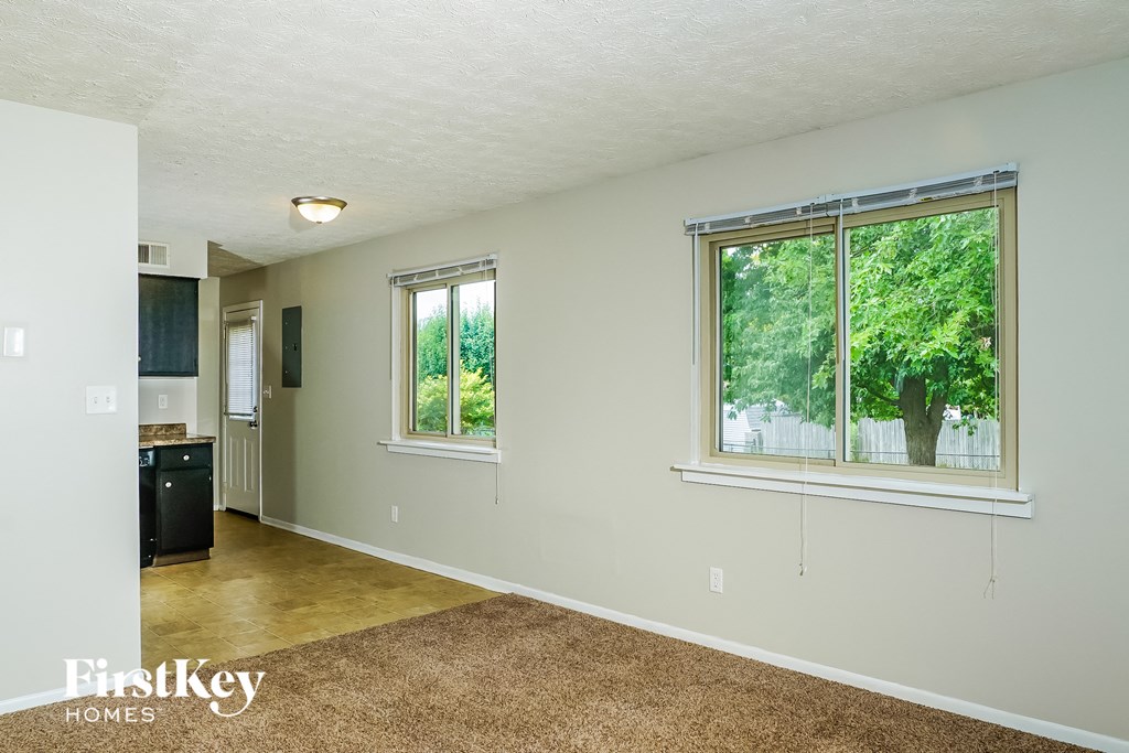 the living room and kitchen of an empty house with a large window