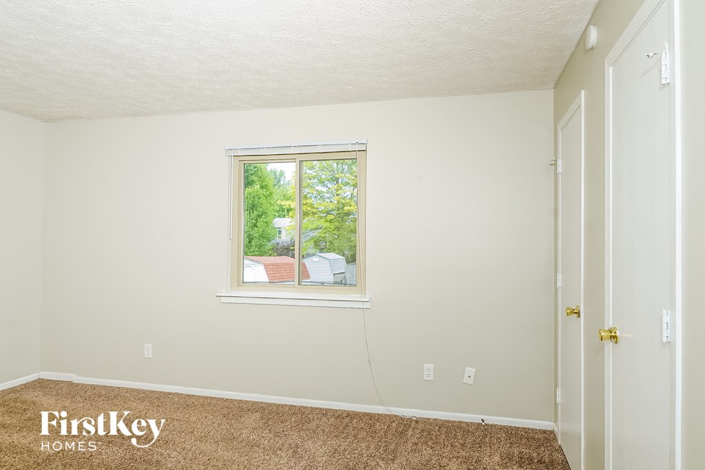 a bedroom with a window and a carpet