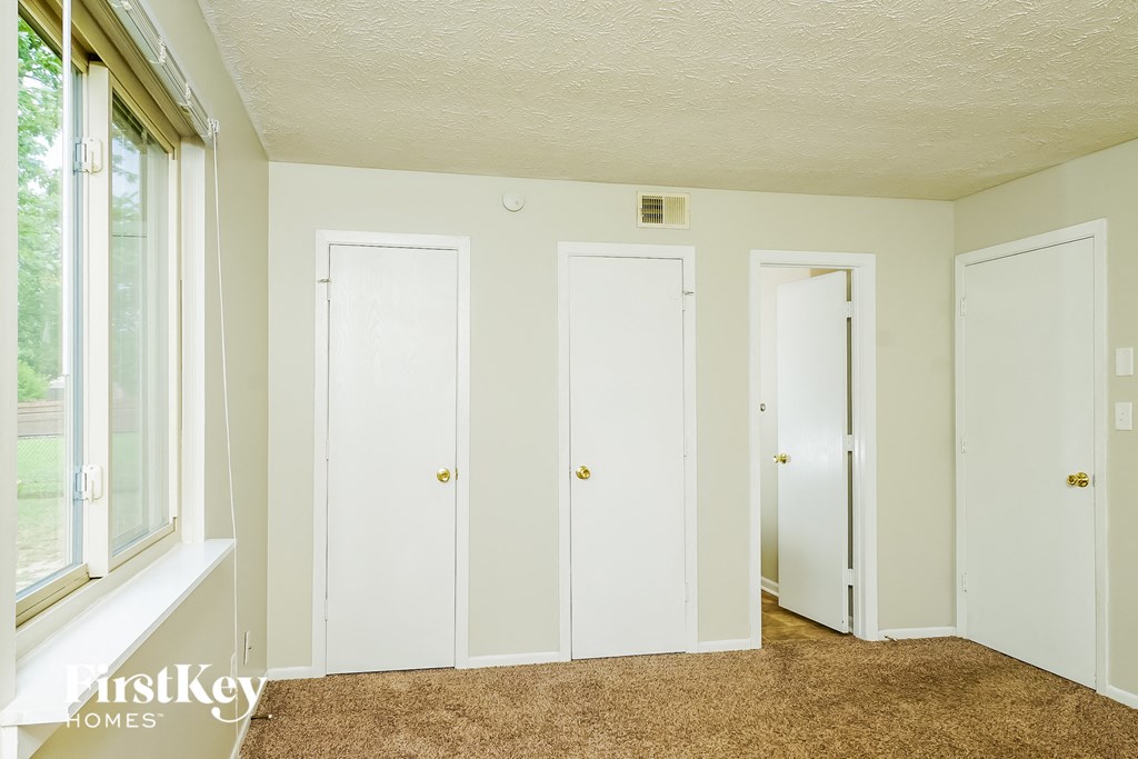 a bedroom with three doors and a window and a carpeted floor