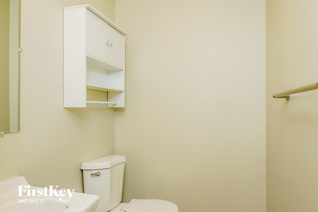 a bathroom with a toilet and a cabinet above it