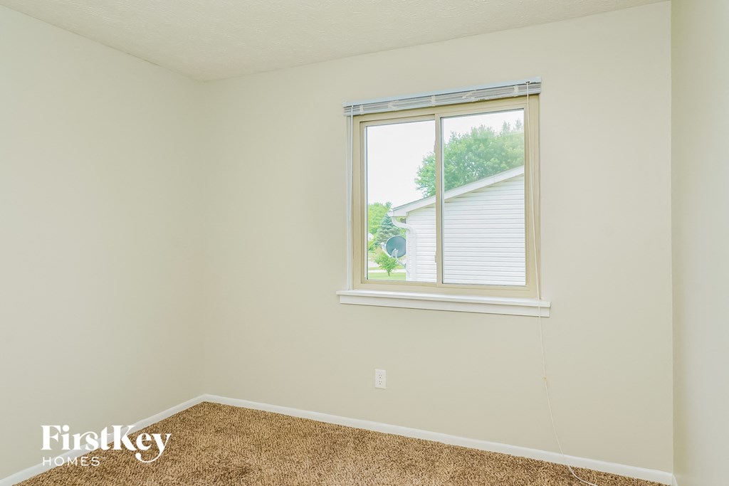 a bedroom with a window and a carpeted floor