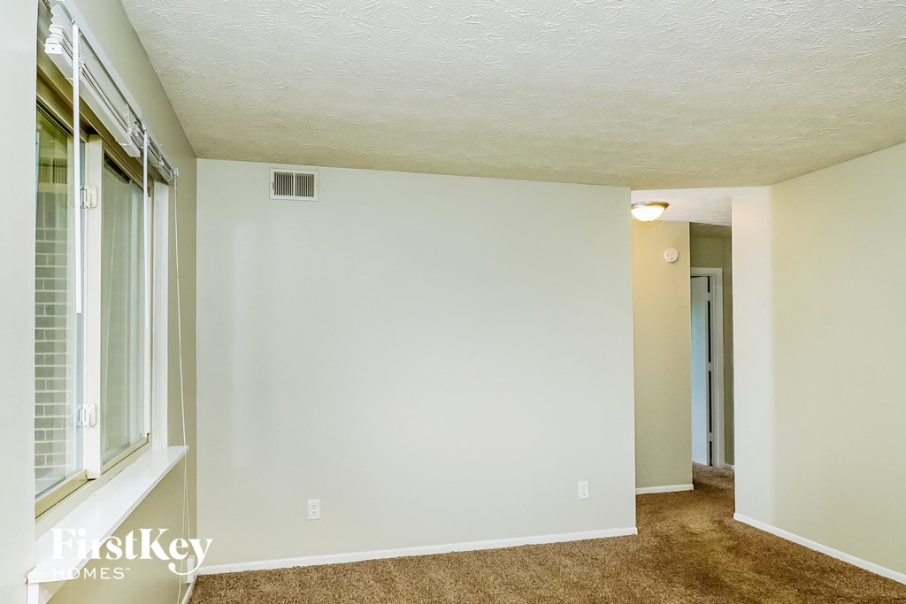 a living room with a large window and a white wall