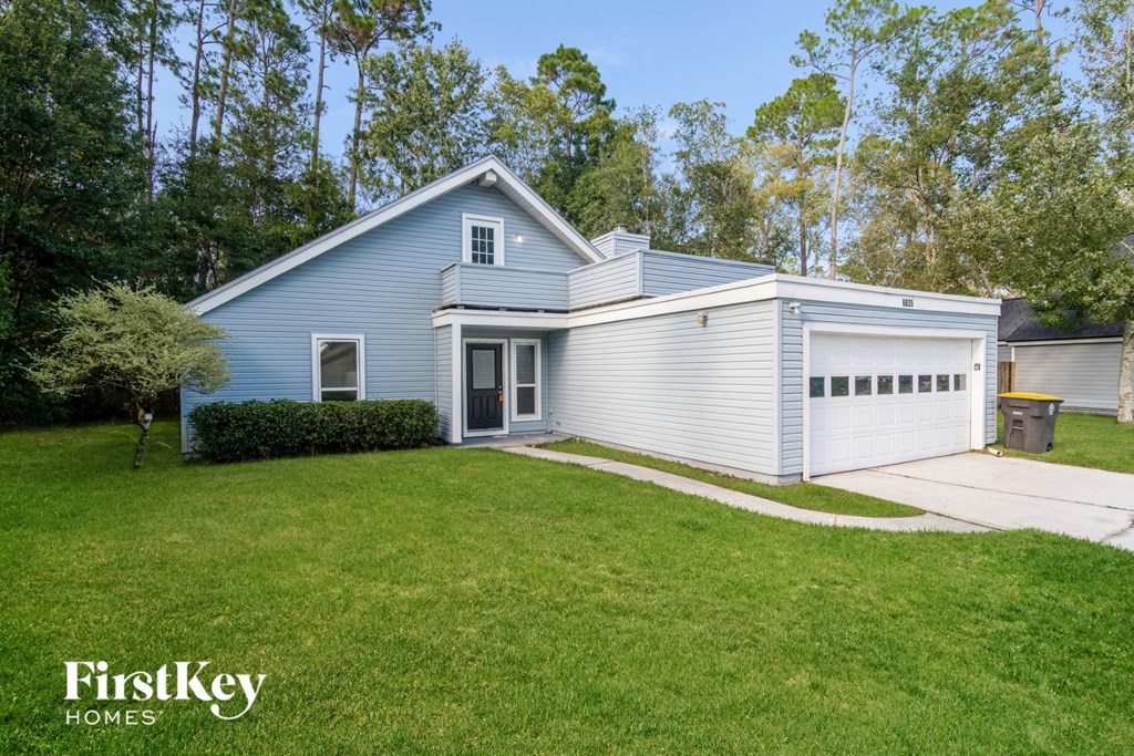 a blue and white house with a lawn and a driveway