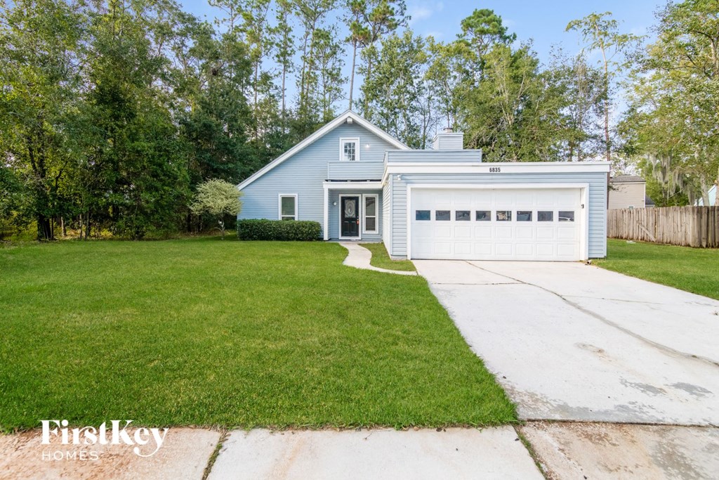 a blue house with a lawn and a white garage door