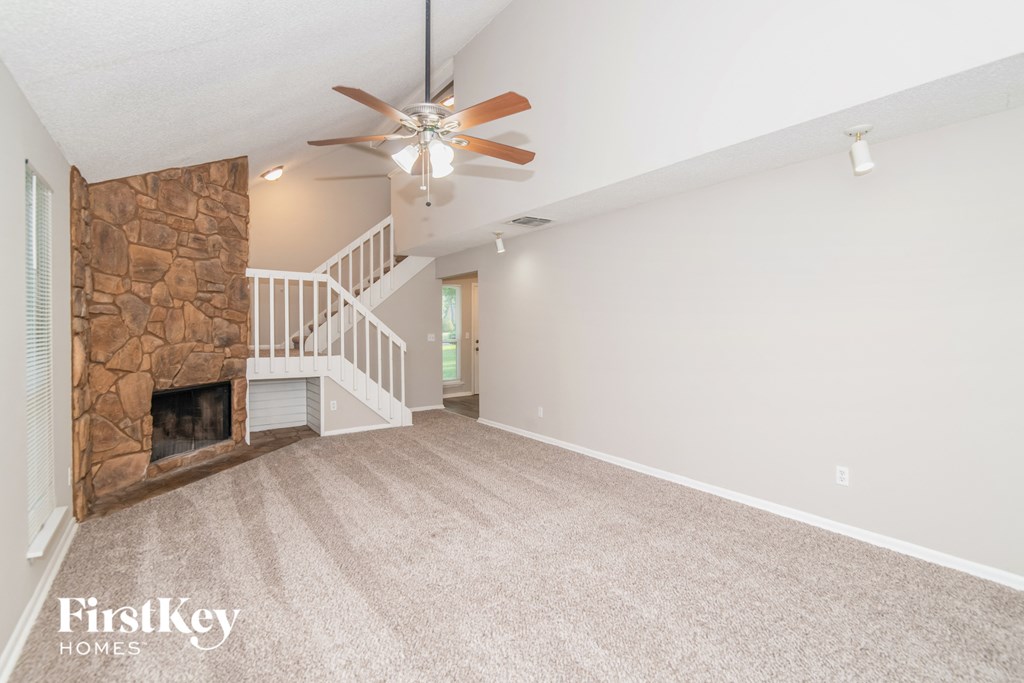 a living room with a stone fireplace and a ceiling fan