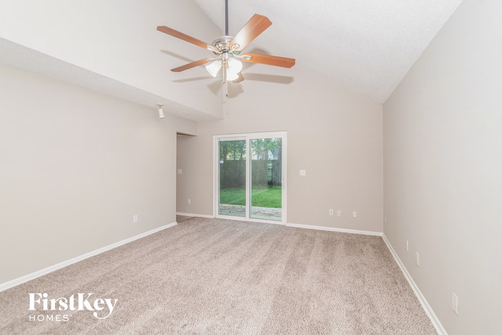 a spacious living room with carpet and a ceiling fan