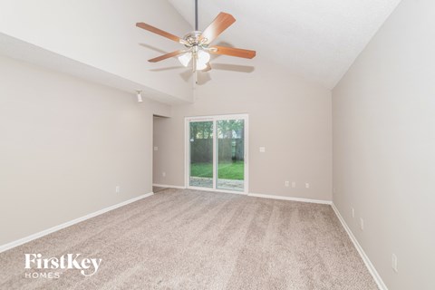 a spacious living room with carpet and a ceiling fan