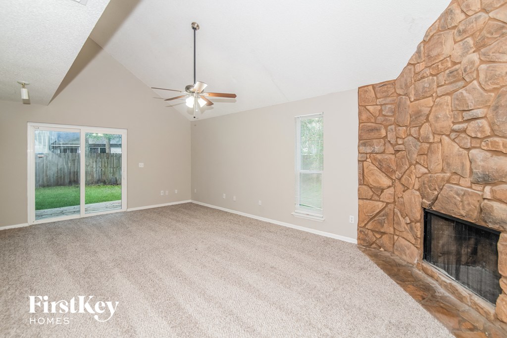 a living room with a stone fireplace and a ceiling fan