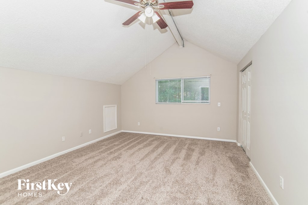 a spacious living room with carpet and a ceiling fan