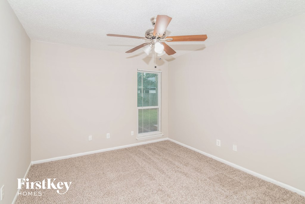 a bedroom with a ceiling fan and a carpet