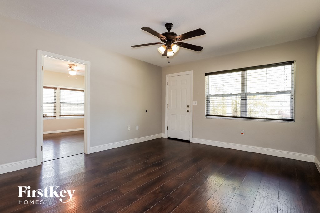 an empty living room with a ceiling fan and a window