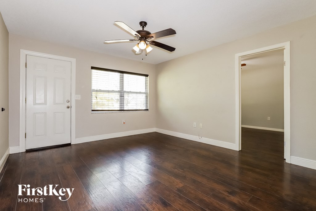 an empty living room with hardwood floors and a ceiling fan