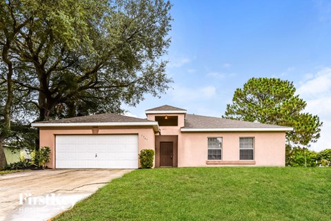 a pink house with a lawn and a garage