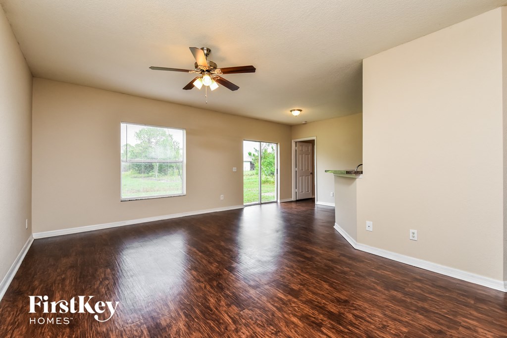 an empty living room with hard wood floors and a ceiling fan