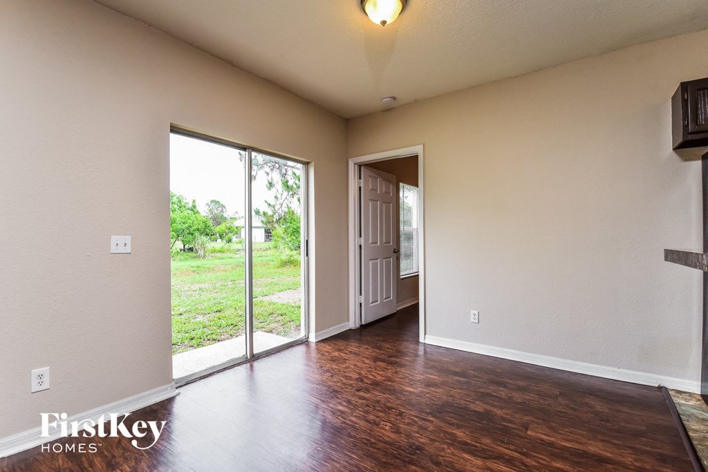 a living room with a door to a hallway and a wood floor