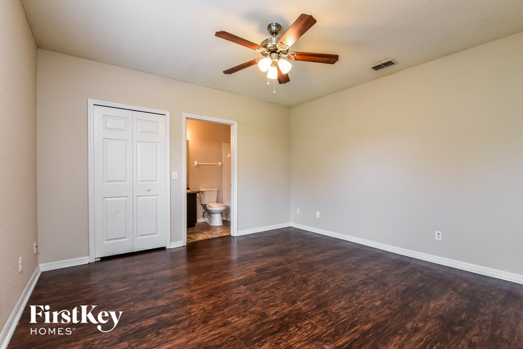 an empty living room with wood flooring and a ceiling fan
