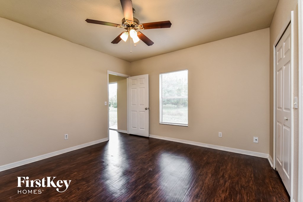 an empty living room with a ceiling fan and wood floors