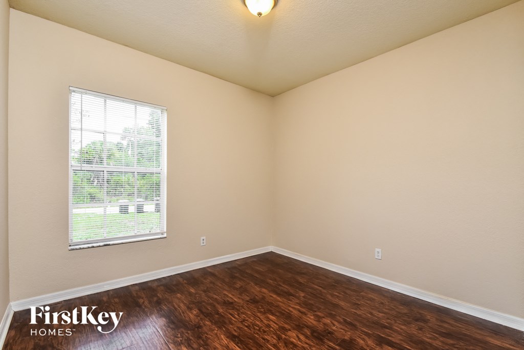 the spacious living room with hardwood flooring and a window