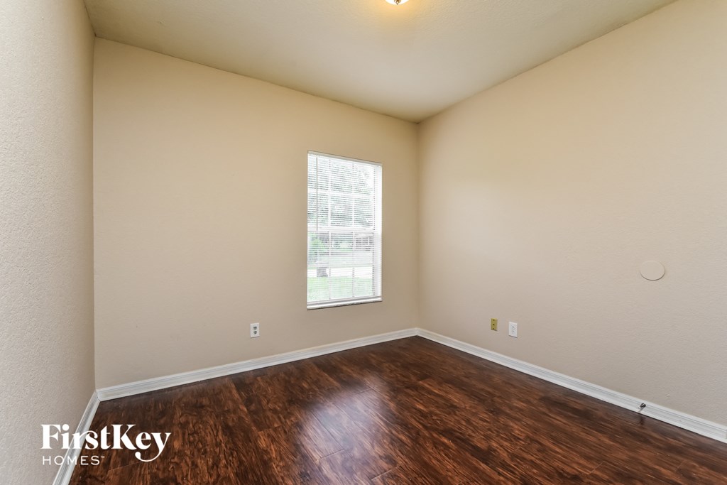 the spacious living room with hardwood flooring and a window