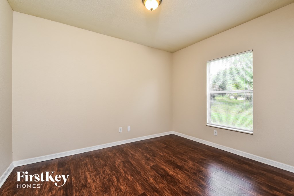 the spacious living room with wood flooring and a large window