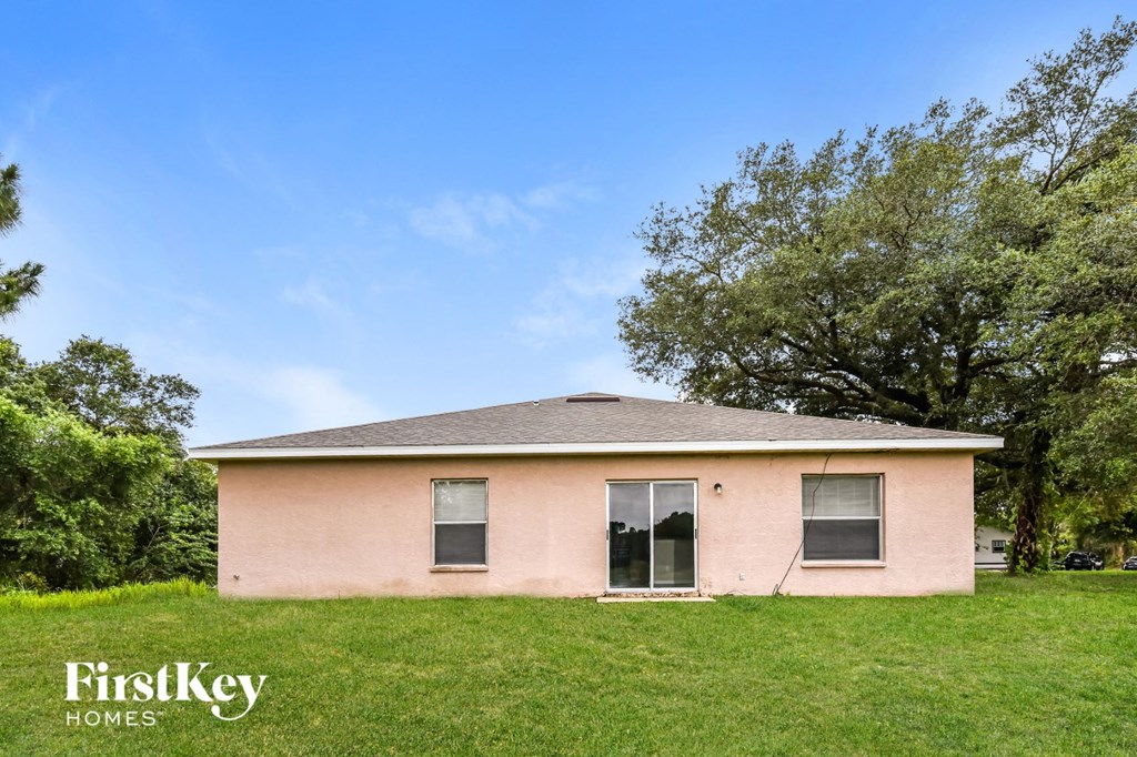a small pink house in a grassy area with trees