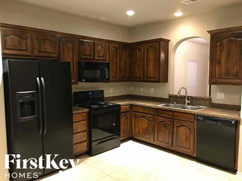 A kitchen with wooden cabinets and black appliances.