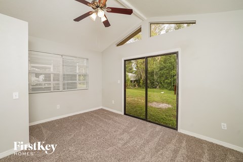 A room with a ceiling fan and sliding glass doors leading to a grassy area.