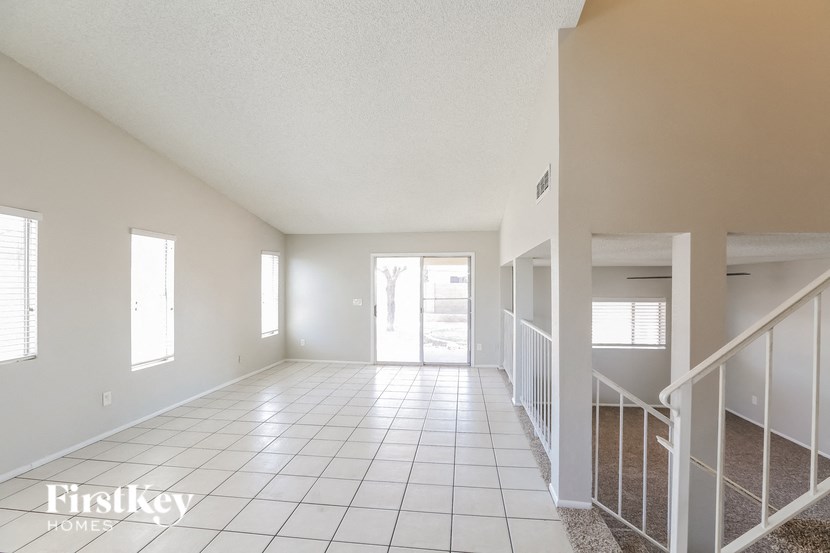 a spacious living room with a tiled floor and a staircase