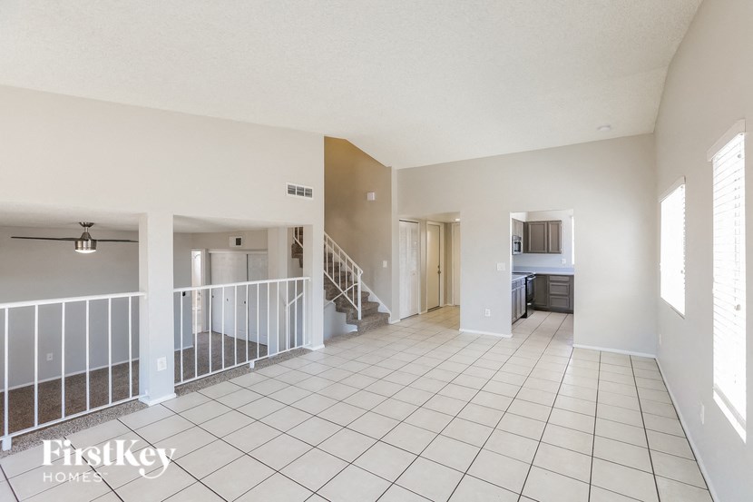 a spacious living room with a white tiled floor and a staircase