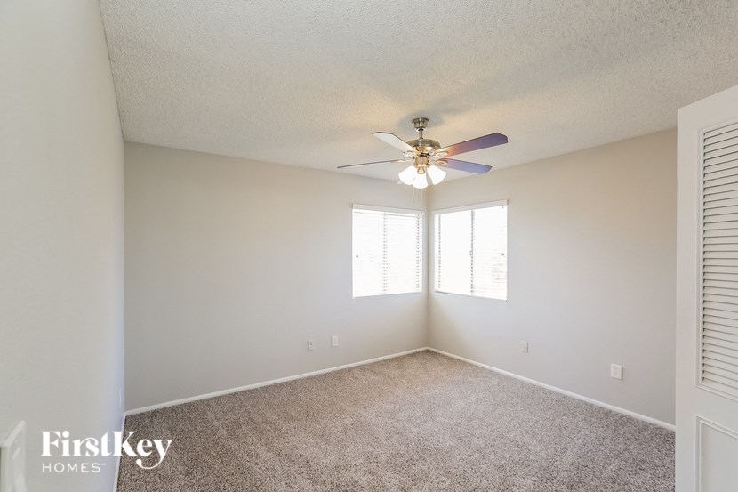 an empty living room with a ceiling fan and a window