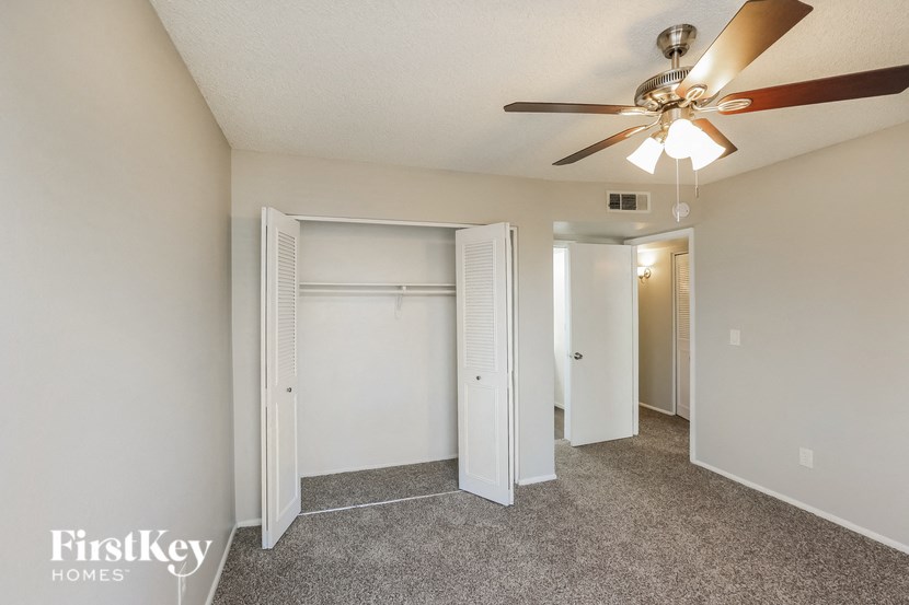 a bedroom with a ceiling fan and a closet