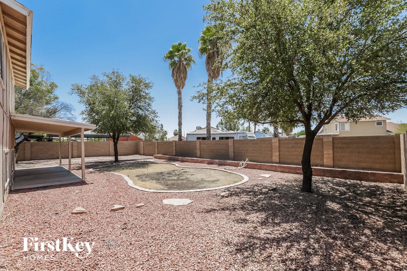 a fenced in backyard with trees and a fountain